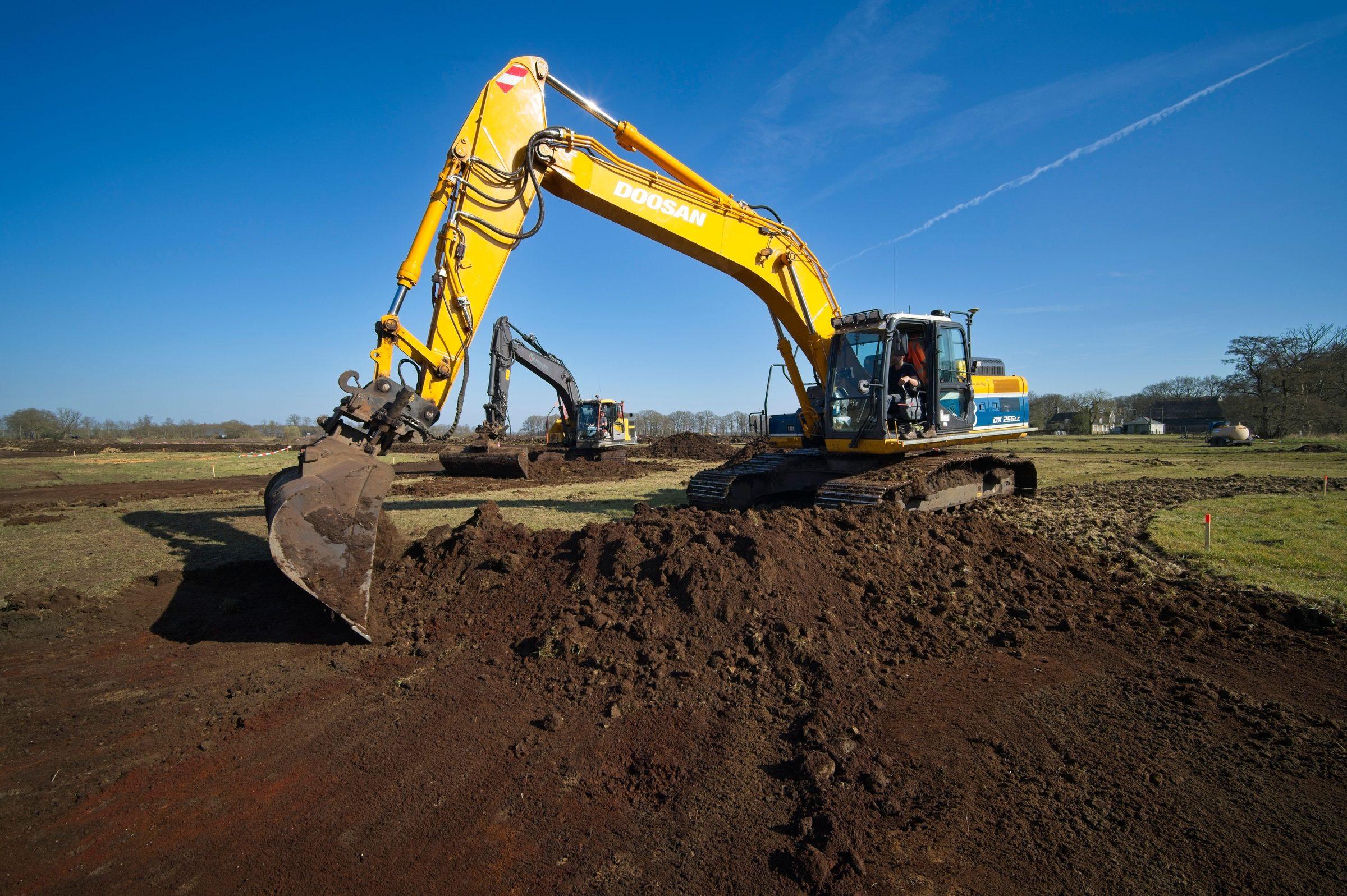 Two excavators leveling a field, low-angle view