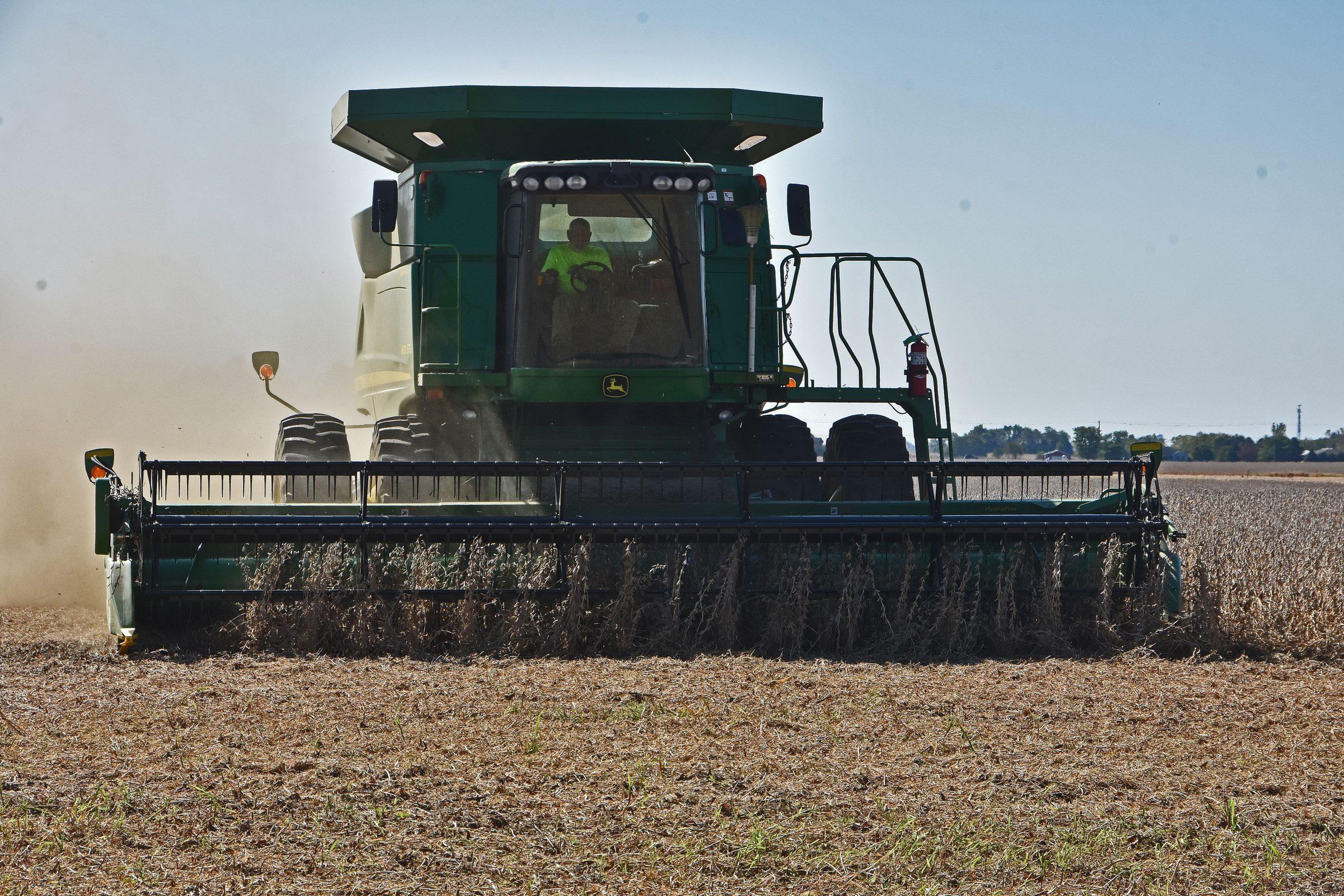 Tractor pulling a seed drill through a field at golden hour