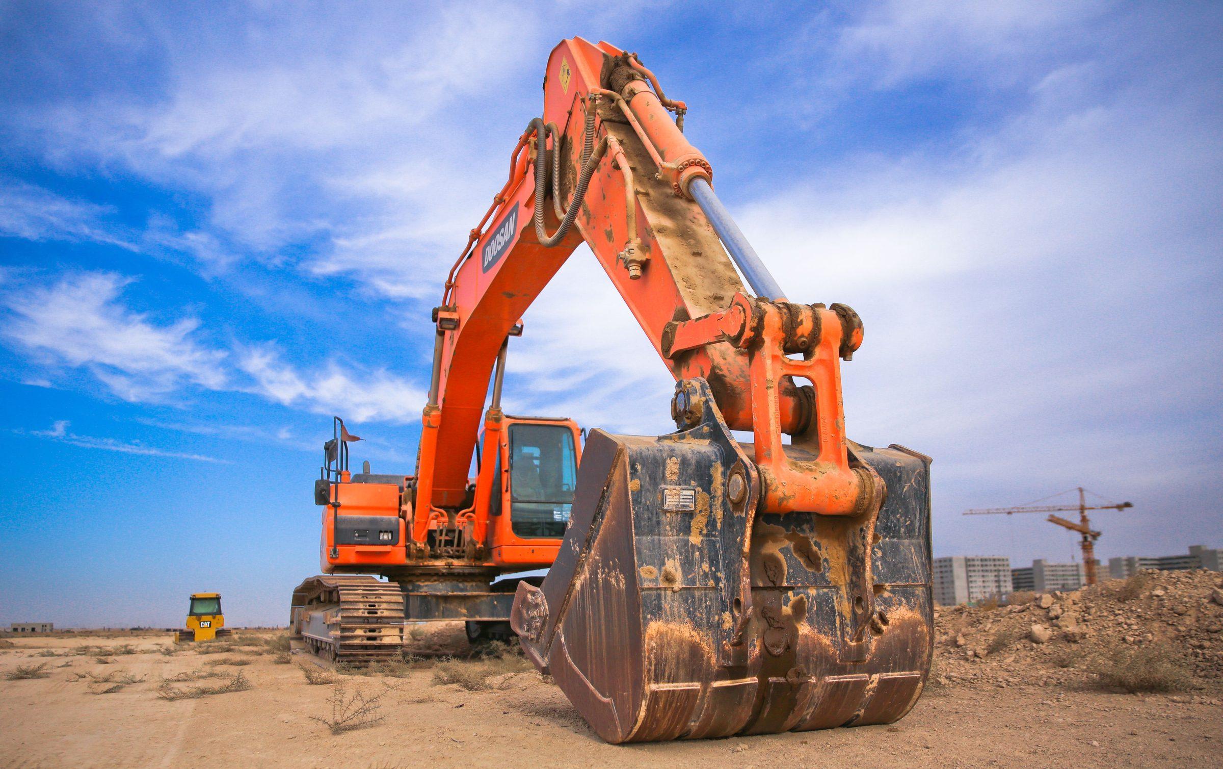 Excavators working a multi-machine construction site with a crane in the background